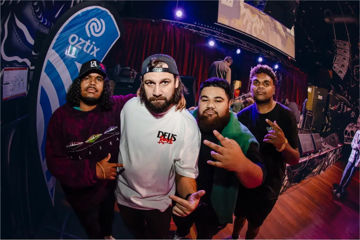 Four musicians posing together in front of an Oztix backdrop